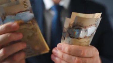 Formally dressed man counting Canadian Dollar bills, close-up. Concept of investment, success, financial prospects or career advancement.