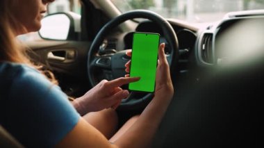 Kadın sürücü arabanın içinde akıllı telefon kullanıyormuş. Yeşil ekranlı Chromakey akıllı telefon. Otomatik navigasyon. İnternet bağımlılığı. Otomobil sigortası uygulaması.