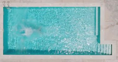 Top down view as a man dives into the pool and swims. Shot with different speed - slow motion and normal.
