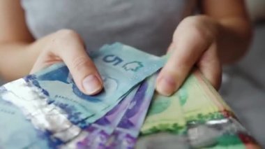 Female hands counting Canadian Dollar bills, close-up. Concept of investment, success, financial prospects or career advancement.