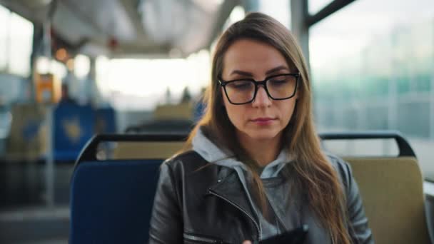 公共交通 坐在电车里戴眼镜的女人用智能手机和朋友聊天和发短信 — 图库视频影像