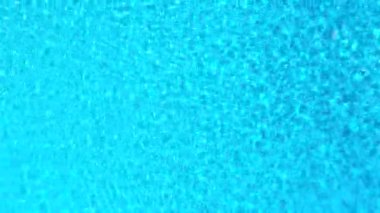 Yüzme havuzundaki saf mavi suyun yüzeyinde ışık yansımaları var. Hava görüntüleri