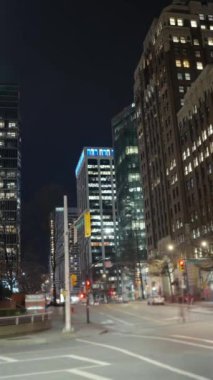 Vertical time lapse crossroads with cars and people crossing street at night, bus moving fast in big city in evening. Time-lapse cars rush hour driveway, pedestrians crossing intersection