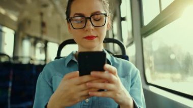 Toplu taşıma. Tramvaydaki gözlüklü kadın akıllı telefon konuşmaları yapıyor ve arkadaşlarıyla mesajlaşıyor. Şehir, şehir, ulaşım.