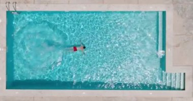 Bir adam havuza dalıp yüzerken yukarıdan aşağıya doğru bak.