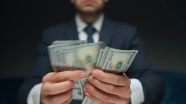 Resmi olarak giyinmiş bir adam Amerikan dolarlarını sayıyor, yakın plan. Yatırım, başarı, finansal beklentiler veya kariyer ilerlemesi kavramı.
