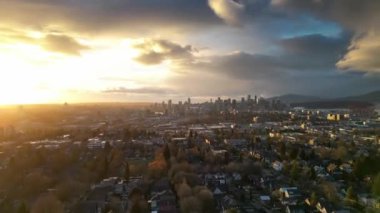 Vancouver 'ın arka planında, BC, Kanada' da bir yerleşim yerinin ve şehir merkezinin hava hızında düşüşü. Yağmurlu bulutlu gökyüzü ile gün batımı.