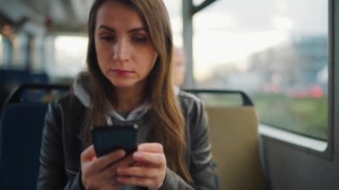 Toplu taşıma. Akıllı telefonları kullanan ve arkadaşlarıyla mesajlaşan bir kadın, ağır çekim. Şehir, şehir, ulaşım.