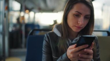 Public transport. Woman using smartphone chatting and texting with friends. City, urban, transportation.
