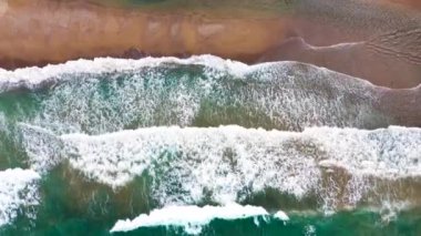 Deniz dalgaları kumlu sahil şeridinde dalgalanırken hiç bitmeyen güzel ve kusursuz görüntülerin drone görüntüsü. Akdeniz kıyısının en üst manzarası, dalgalar ıssız kumsala ulaşıyor. Güzel