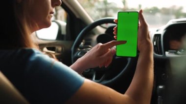 Kadın sürücü arabanın içinde akıllı telefon kullanıyormuş. Yeşil ekranlı Chromakey akıllı telefon. Otomatik navigasyon. İnternet bağımlılığı. Otomobil sigortası uygulaması.