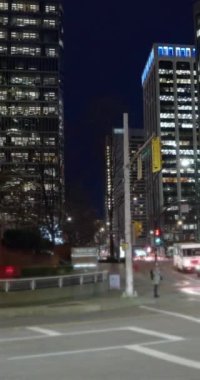 Vertical time lapse crossroads with cars and people crossing street at night, bus moving fast in big city in evening. Time-lapse cars rush hour driveway, pedestrians crossing intersection
