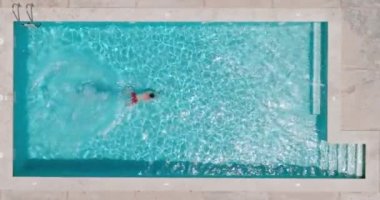 Top down view as a man dives into the pool and swims. Slow motion
