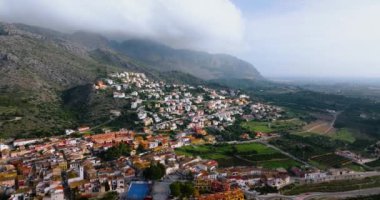 Aerial view of the landscape near the city of Denia - clouds float over the mountain, village on the side of a mountain, orange fields. Province of Alicante, Spain