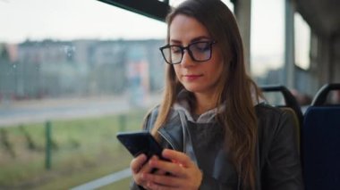 Toplu taşıma. Tramvaydaki gözlüklü kadın akıllı telefon konuşmaları yapıyor ve arkadaşlarıyla mesajlaşıyor. Şehir, şehir, ulaşım.