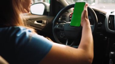 Kadın sürücü arabanın içinde akıllı telefon kullanıyormuş. Yeşil ekranlı Chromakey akıllı telefon. Otomatik navigasyon. İnternet bağımlılığı. Otomobil sigortası uygulaması.