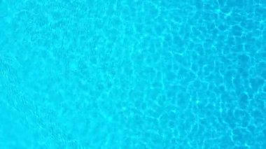 Yüzme havuzundaki saf mavi suyun yüzeyinde ışık yansımaları var. Hava görüntüleri
