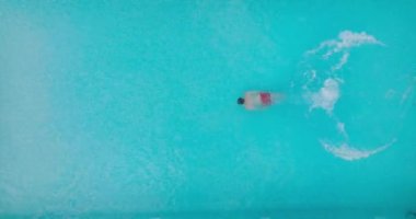 Bir adam havuza dalıp yüzerken yukarıdan aşağıya doğru bak.