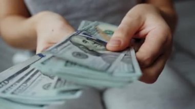 Kadın eli, Amerikan dolarlarını sayıyor, yakın plan. Yatırım, başarı, finansal beklentiler veya kariyer ilerlemesi kavramı.