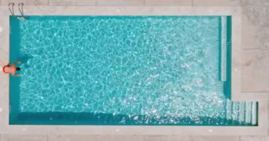 Top down view as a man dives into the pool and swims. Slow motion