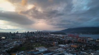 Vancouver 'ın arka planında, BC, Kanada' da bir banliyö yerleşim bölgesinin ve şehir merkezinin havadan görüntüsü. Yağmurlu bulutlu gökyüzü ile gün batımı.