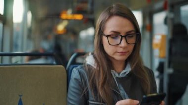Toplu taşıma. Tramvaydaki gözlüklü kadın akıllı telefon konuşmaları yapıyor ve arkadaşlarıyla mesajlaşıyor. Şehir, şehir, ulaşım.