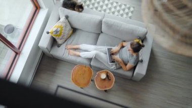 Kadının dizüstü bilgisayar kullanırken, evdeki kanepede yatarken.