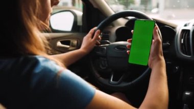 Kadın sürücü arabanın içinde akıllı telefon kullanıyormuş. Yeşil ekranlı Chromakey akıllı telefon. Otomatik navigasyon. İnternet bağımlılığı. Otomobil sigortası uygulaması.