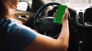 Kadın sürücü arabanın içinde akıllı telefon kullanıyormuş. Yeşil ekranlı Chromakey akıllı telefon. Otomatik navigasyon. İnternet bağımlılığı. Otomobil sigortası uygulaması.