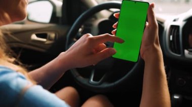 Kadın sürücü arabanın içinde akıllı telefon kullanıyormuş. Yeşil ekranlı Chromakey akıllı telefon. Otomatik navigasyon. İnternet bağımlılığı. Otomobil sigortası uygulaması.