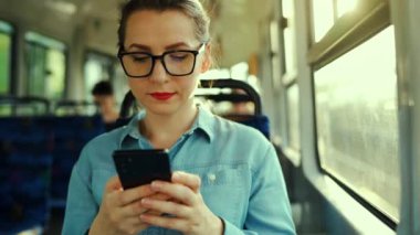 Toplu taşıma. Tramvaydaki gözlüklü kadın akıllı telefon konuşmaları yapıyor ve arkadaşlarıyla mesajlaşıyor. Şehir, şehir, ulaşım. Yavaş çekim