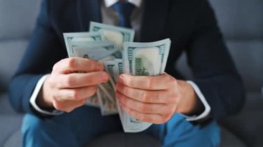 Resmi olarak giyinmiş bir adam Amerikan dolarlarını sayıyor, yakın plan. Yatırım, başarı, finansal beklentiler veya kariyer ilerlemesi kavramı.