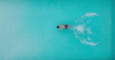 Top down view as a man dives into the pool and swims. Slow motion