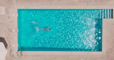 Top down view as a man dives into the pool and swims. Slow motion