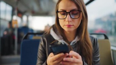 Toplu taşıma. Tramvaydaki gözlüklü kadın akıllı telefon konuşmaları yapıyor ve arkadaşlarıyla mesajlaşıyor. Şehir, şehir, ulaşım.