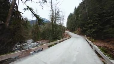 Büyük taşların arasında akan ve kıyılarda ağaçlarla çevrili bir dağ nehrinin üzerinden hızlı bir uçuş. Chilliwack, British Columbia, Kanada. POV FPV insansız hava aracı ile filme alındı.