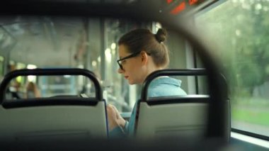 Toplu taşıma. Tramvaydaki gözlüklü kadın akıllı telefon konuşmaları ve arkadaşlarıyla mesajlaşmalar yapıyor. Şehir, şehir, ulaşım.