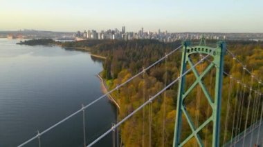 Şafakta Lions Gate Köprüsü ve Stanley Parkı 'nın havadan görüntüsü. Arka planda Vancouver şehir merkezi var. Farklı hızlarda çekilmiş. Normal ve hızlandırılmış. Britanya Kolombiyası Kanada 