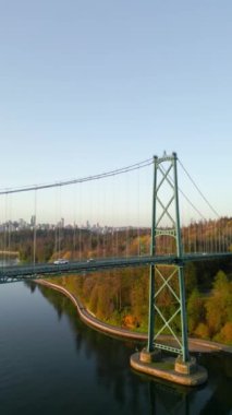Dikey video. Şafakta Lions Gate Köprüsü ve Stanley Parkı 'nın havadan görüntüsü. Arka planda Vancouver şehir merkezi var. Britanya Kolombiyası Kanada. 