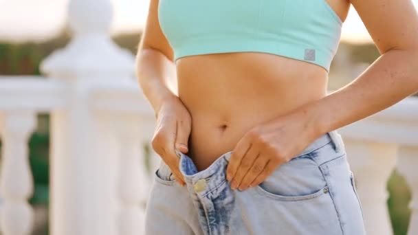 女性は自宅のバルコニーで減量をお楽しみください 大きなジーンズのスリム女性の体 健康的な食事の結果 — ストック動画