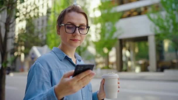 Donna Caucasica Occhiali Piedi Città Utilizzando Smartphone Bere Caffè Rallentatore — Video Stock