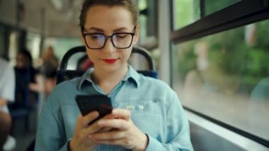 Toplu taşıma. Tramvaydaki gözlüklü kadın akıllı telefon konuşmaları yapıyor ve arkadaşlarıyla mesajlaşıyor. Şehir, şehir, ulaşım