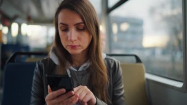 Toplu taşıma. Tramvayda akıllı telefon kullanan, arkadaşlarıyla mesajlaşan bir kadın. Şehir, şehir, ulaşım.