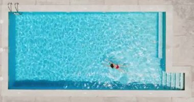 Top down view of a woman in red swimsuit swimming in the pool. Summer lifestyle