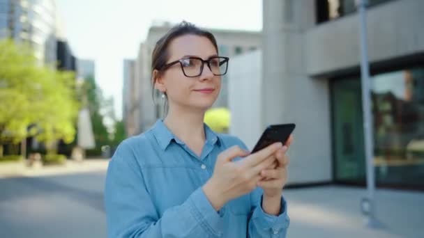 Běloška Brýlích Chodí Městě Používá Smartphone Mrakodrapy Jsou Pozadí Komunikace — Stock video