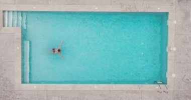 Kırmızı şortlu, havuzda yüzen bir adamın yukarıdan görünüşü, yavaş çekim. Yaz yaşam tarzı