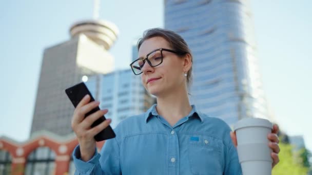Caucasian Woman Glasses Walking City Using Smartphone Drinking Coffee Skyscrapers — Stock Video