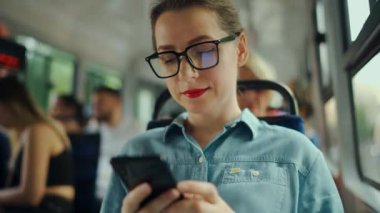 Toplu taşıma. Tramvaydaki gözlüklü kadın akıllı telefon konuşmaları yapıyor ve arkadaşlarıyla mesajlaşıyor. Şehir, şehir, ulaşım