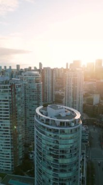 Dikey video. Vancouver, British Columbia, Kanada şehir merkezindeki gökdelenlerin günbatımında hava görüntüsü.