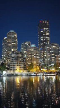 Geceleri Vancouver 'ın şehir merkezindeki göz kamaştırıcı manzara. Binalar suya yansıyor. False Creek, British Columbia, Kanada.